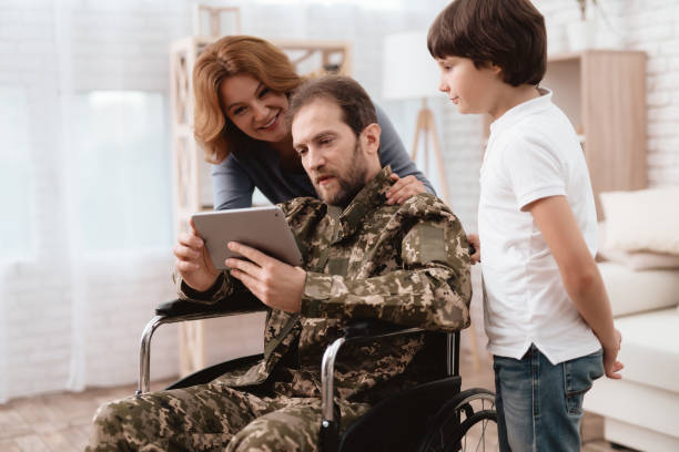 the veteran in a wheelchair came back from the army. a man in uniform in a wheelchair with his family. - physical impairment wheelchair disabled accessibility imagens e fotografias de stock