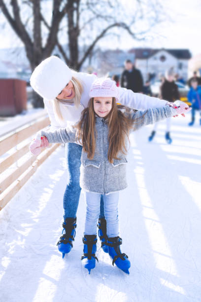istock Mother Helping Her daughter Learn to Ice Skate 897471318