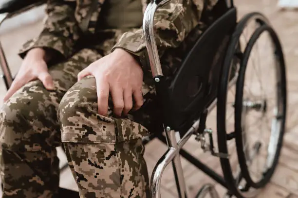 Veteran in wheelchair returned from army. Close-up photo veteran in a wheelchair. Wheelchairs and legs in military uniform.