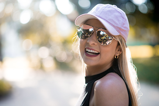 Portrait of a happy young woman using a sunglasses in a beautiful day.