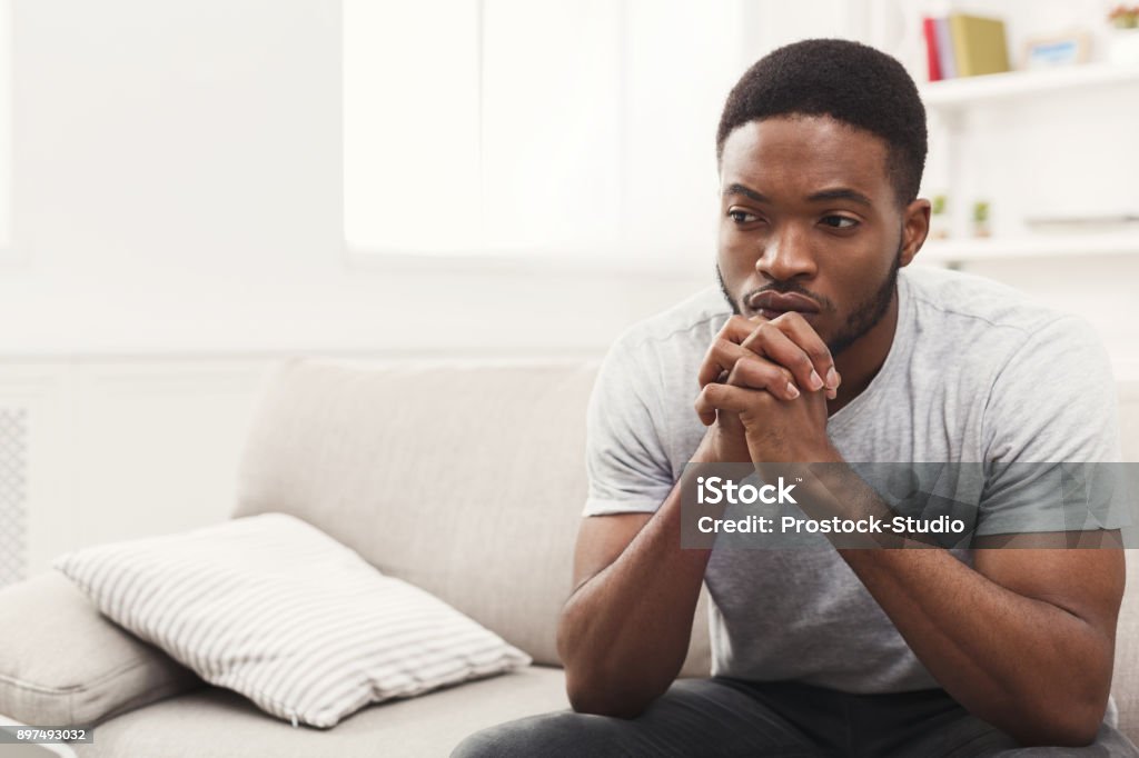 Disappointed young african-american man at home Young african-american man sitting at home. Sad guy sitting on the couch , copy space Men Stock Photo