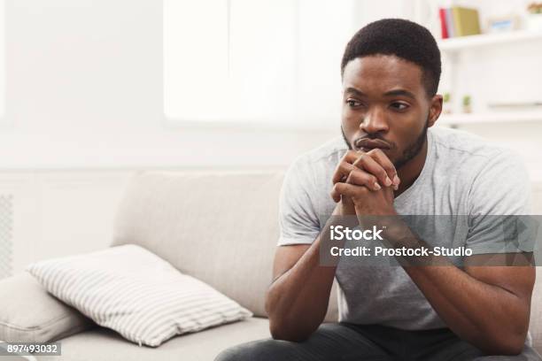 Disappointed Young Africanamerican Man At Home Stock Photo - Download Image Now - Men, Sadness, Contemplation