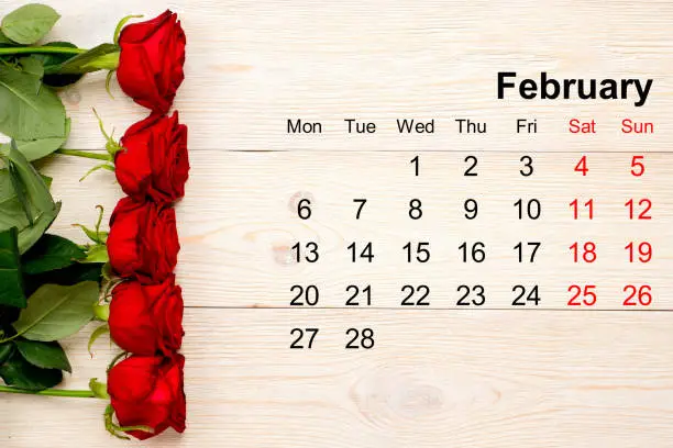 February calendar with red roses on white table
