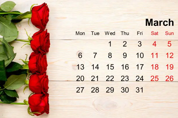 March calendar with red roses on white desk
