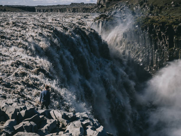 istock tourist standing on cliff and looking at Dettifoss waterfall in Iceland 897498612