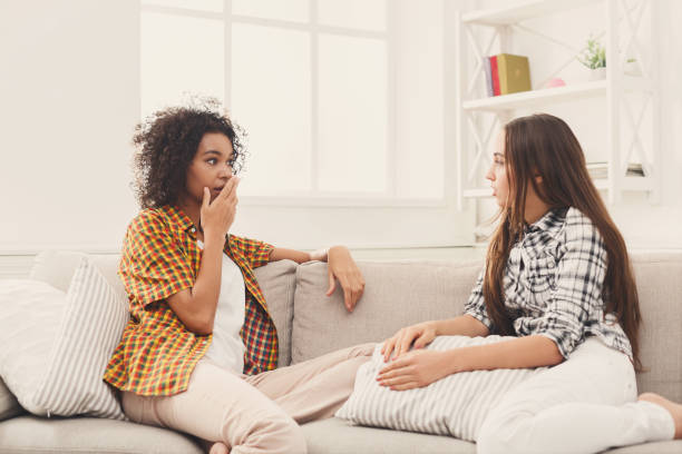 istock Two young female friends conversing at home 897498830
