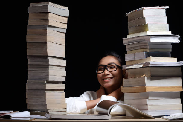 istock Girl in white shirt reading many textbooks on table with many high stacking 897503416