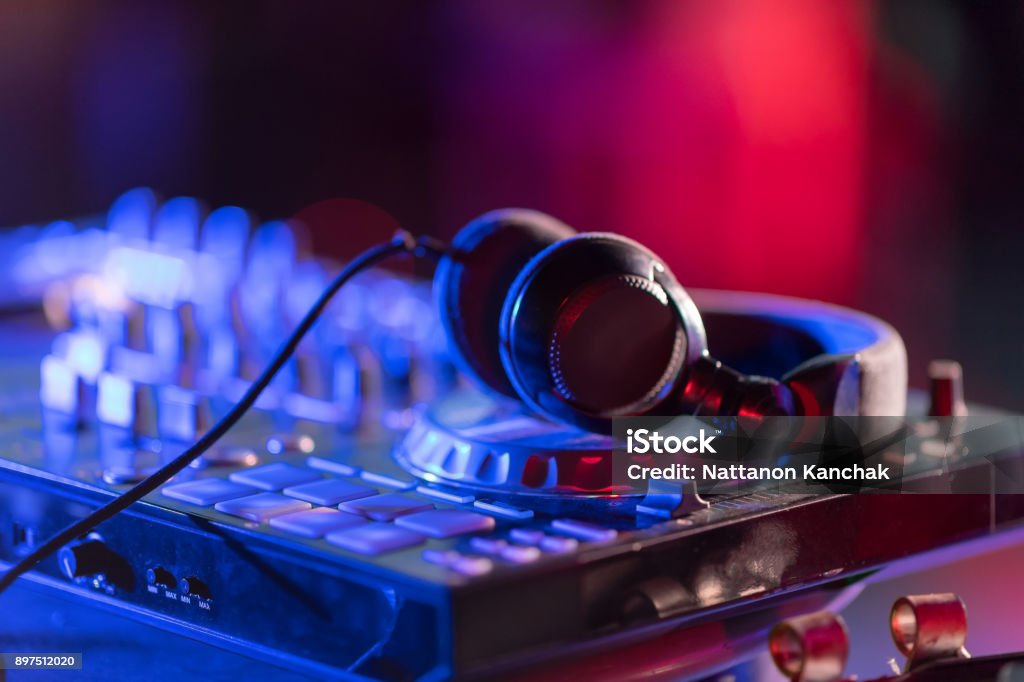 The DJ console cd mp4 deejay mixing desk Ibiza house music party in nightclub with colored disco lights. In selective focus of Pro dj controller.The DJ console cd mp4 deejay mixing desk Ibiza house music party in nightclub with colored disco lights. Wedding Stock Photo