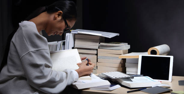 istock Girl in white shirt reading many textbooks on table with many high stacking 897512134