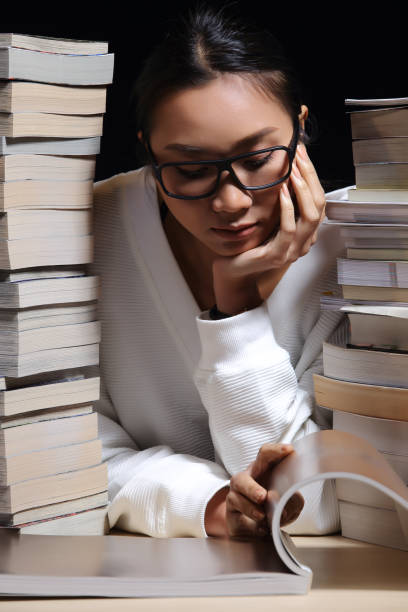 istock Girl in white shirt reading many textbooks on table with many high stacking 897515776