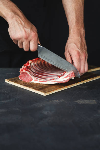 istock Chef cutting rack of lamb on wooden board in kitchen 897516222