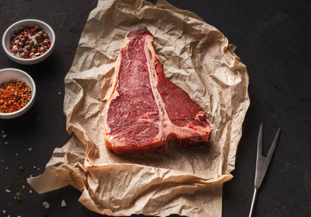 istock Raw t-bone steak on craft papper on dark background 897516814