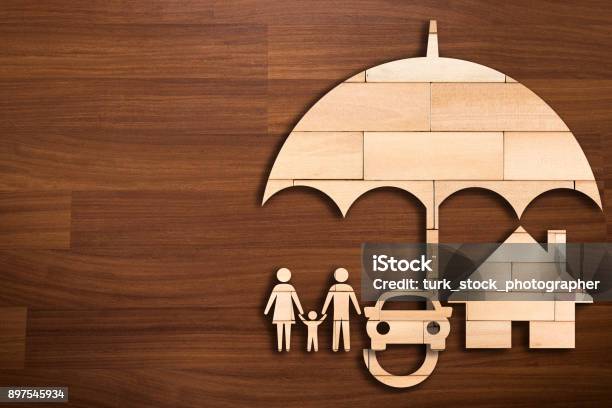 Wooden Silhouette Of Family Under Umbrella Concept Of Insurance Stock Photo - Download Image Now