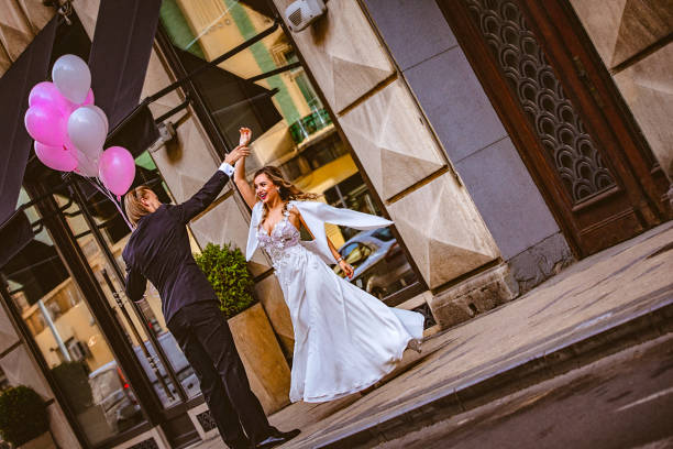 istock Affectionate bride and groom, holding hands, happily dance down the street 897551592