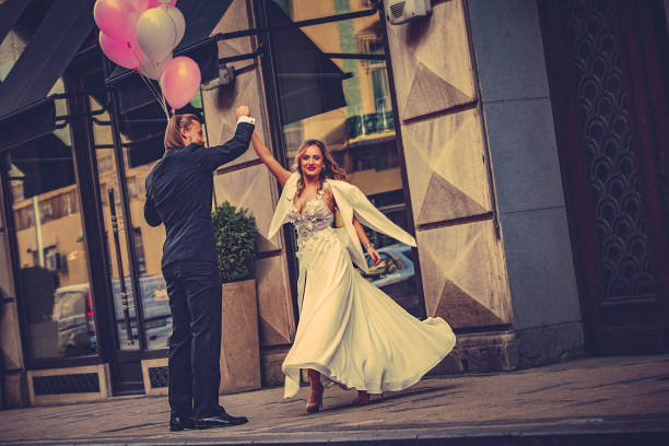 istock Affectionate bride and groom, holding hands, happily dance down the street 897551594