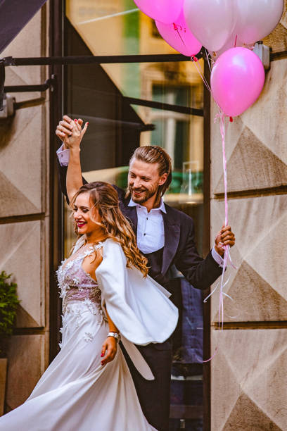 istock Affectionate bride and groom, holding hands, happily dance down the street 897551596