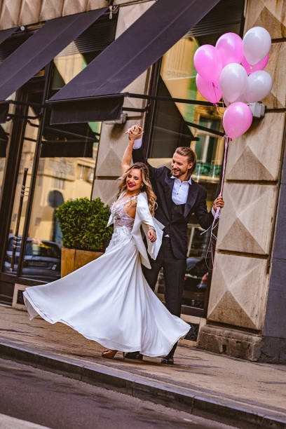 istock Affectionate bride and groom, holding hands, happily dance down the street 897553662