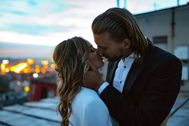 istock Affectionate bride and groom, embraces and kisses on the rooftop at sunset. 897557874