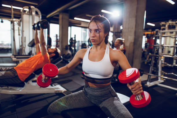 istock Young woman working out with dumbbells at gym 897564240