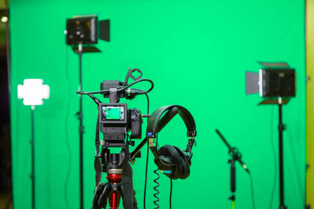 緑の背景に指向性マイク、ヘッドフォン led 投光照明三脚にカメラ。クロマ ・ キー。緑色の画面 - パビリオン 写真 ストックフォトと画像