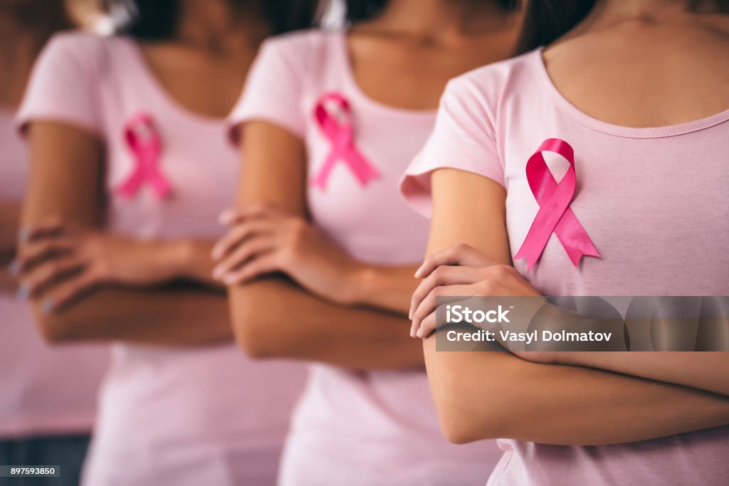 Breast cancer awareness. Cropped image of group of young multiracial woman with pink ribbons are struggling against breast cancer. Breast cancer awareness concept. Breast Cancer Stock Photo