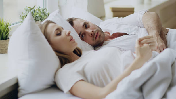 primo piano di coppia con problemi di relazione con conversazione emotiva mentre si è sdraiati a letto a casa - wife husband discussion couple foto e immagini stock