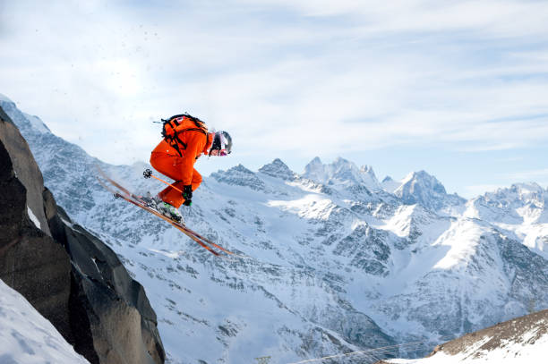 istock A professional skier makes a jump-drop from a high cliff against a blue sky leaving a trail of snow powder in the mountains 897599610