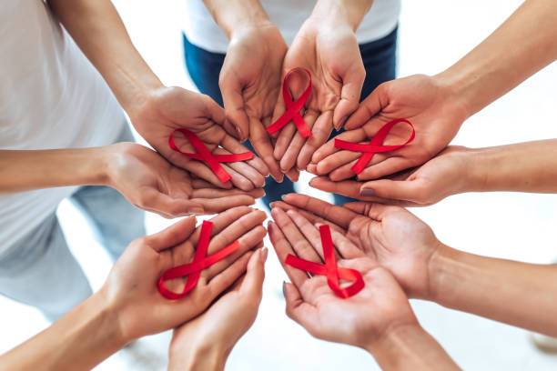 AIDS awareness concept. Group of young multiracial woman with red ribbons in hands are struggling against HIV/AIDS. AIDS awareness concept. aids stock pictures, royalty-free photos & images