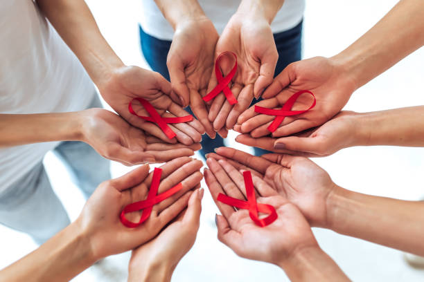 AIDS awareness concept. Group of young multiracial woman with red ribbons in hands are struggling against HIV/AIDS. AIDS awareness concept. hiv stock pictures, royalty-free photos & images