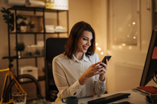 istock Young woman typing a message on her phone, working late into the night 897618910