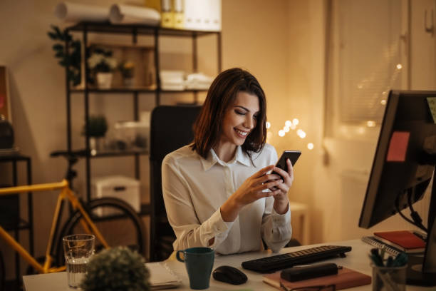istock Young woman typing a message on her phone, working late into the night 897619018