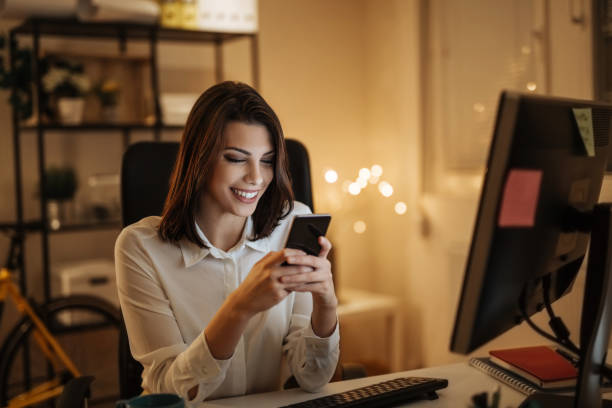 istock Young woman typing a message on her phone, working late into the night 897619176