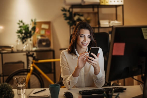 istock Young woman typing a message on her phone, working late into the night 897619178