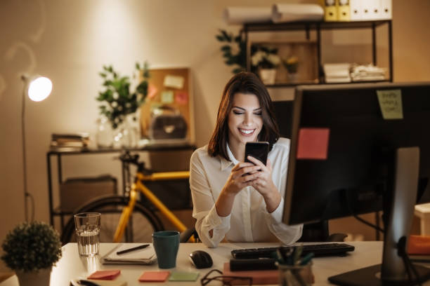istock Young woman typing a message on her phone, working late into the night 897619260