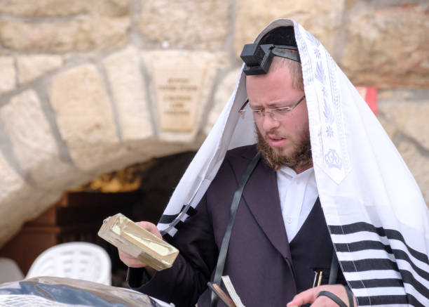 um homem está rezando perto da parede ocidental na cidade velha de jerusalém, o lugar de holliest para o povo judeu - talit - fotografias e filmes do acervo