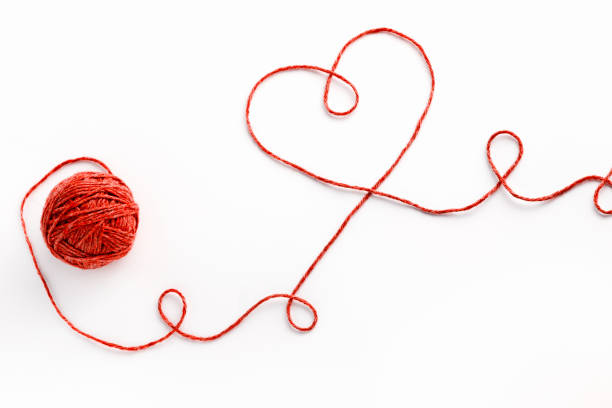 istock Wool ball and thread in shape of heart on white background 897630938