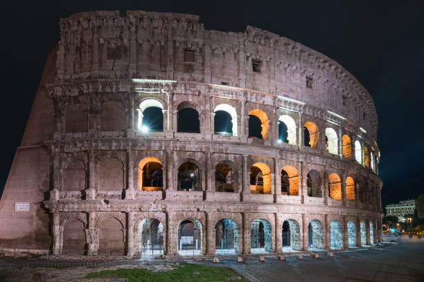 Low angle view of Coliseum at dusk in Rome, Italy. Image taken with zoom in zoom out technic. Full frame image. Lights shining from windows to the outside. Horizontal composition. Outdoors. It also known as the Flavian Amphitheatre. Coliseum is an oval amphitheatre in the centre of the city of Rome, Italy. Built of concrete and sand. It is the largest amphitheatre ever built. It was used for gladiatorial contests and public spectacles such as mock sea battles, animal hunts, executions, re-enactments of famous battles, and dramas based on Classical mythology.