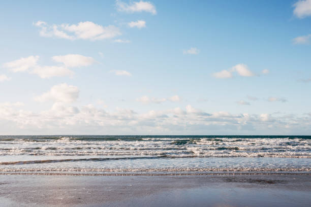 Small waves rolling into a beach on the coast of North Devon, England