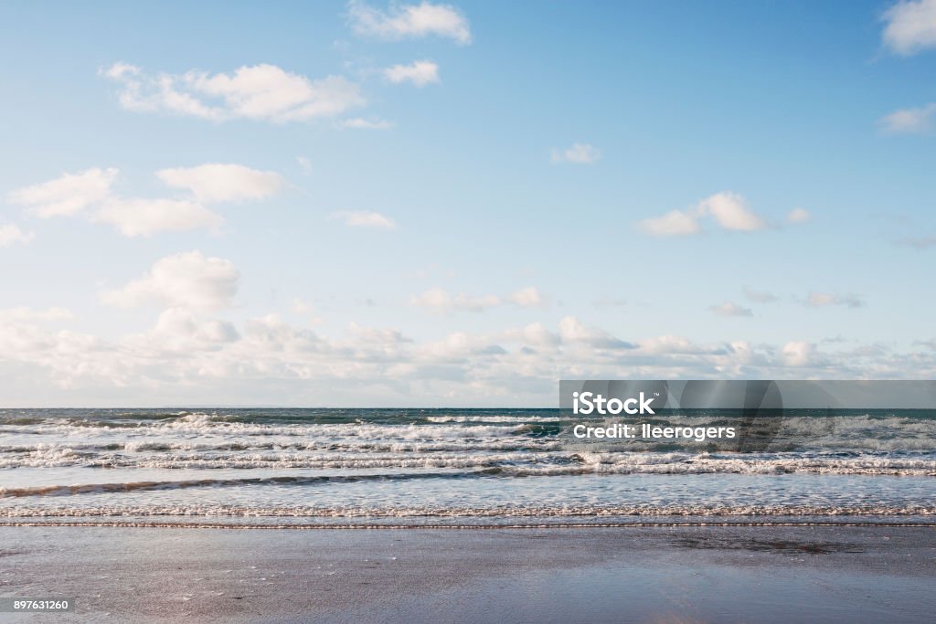 Small waves rolling into a beach on the coast of North Devon, England Look out to sea from Croyde beach at the waves breaking on the shore. It is a popular beach on the North coast of Devon in South West England. Croyde Stock Photo