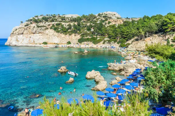 Beachgoers enjoy famous Anthony Quinn Bay beach in Rhodes, Greece