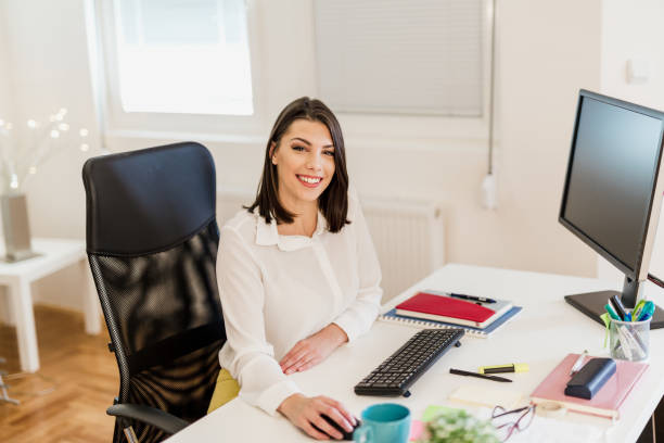 istock Young woman working in her office, typing on a desktop PC keyboard 897656442