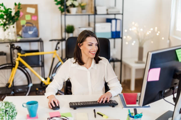 istock Young woman working in her office, typing on a desktop PC keyboard 897656694