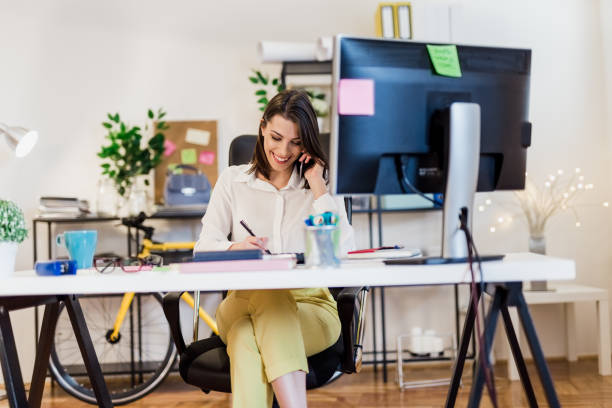 istock Young woman working in her office, talking over the phone 897661090