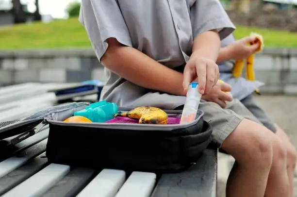 Young boy with a packed lunch takes out his anaphylaxis auto injector.