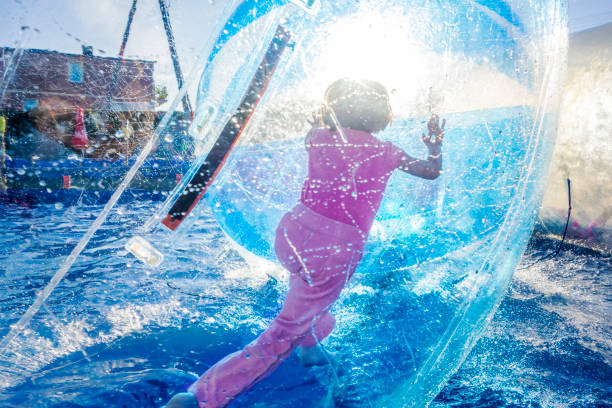 Girl Inside Walking Ball Young girl playing inside a floating water walking ball. zorb ball stock pictures, royalty-free photos & images