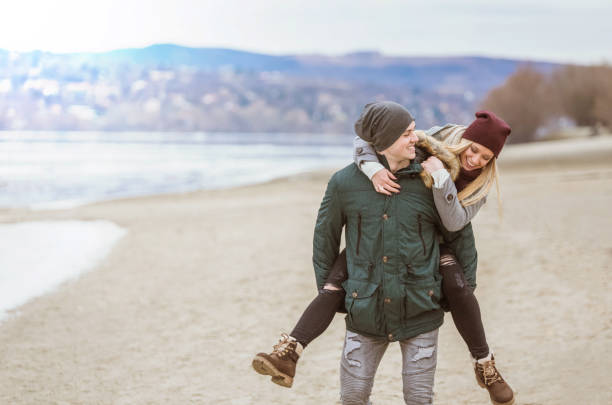 szczęśliwa młoda para w zimowy dzień. - beach couple satisfaction playing zdjęcia i obrazy z banku zdjęć