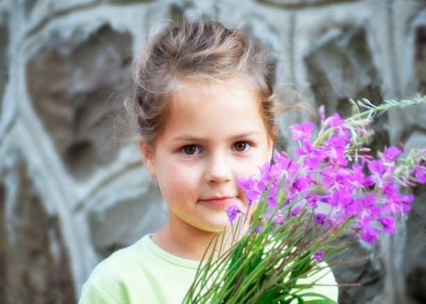 Adorable smiling little girl holding daffodils by the window