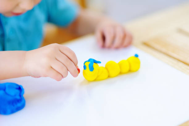 istock Creative boy playing with colorful modeling clay at kindergarten 897755328
