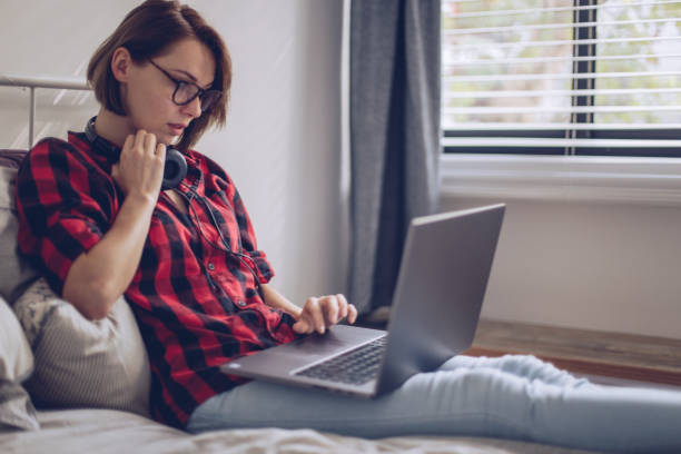 istock Beautiful young woman using her laptop in the bed 897755700