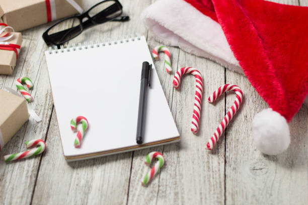 istock Christmas and New Year Items with Copy Space Santa Cap Notepad Pen Glasses and decorated Gift Boxes 897803272